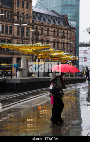 Manchester, UK 4th February, 2016. UK Weather. Heavy rain arrives in the northwest as pedestrians cross near the new tram station in Exchange Square, Stock Photo