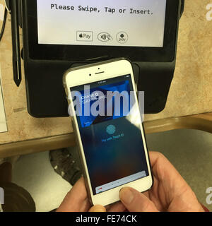 A man uses only his thumbprint to pay for groceries using Apple Pay with Touch ID on an IPhone 6S Plus in Southern California. Stock Photo