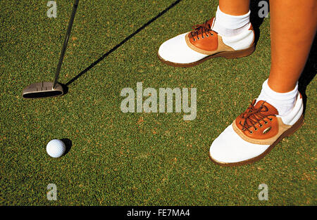 Female golf player with shoes, ball and club on green Stock Photo