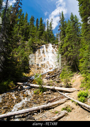 A woman enjoys sitting in Point Lace Falls on a beautiful summer day; Yoho National Park, near Field, British Columbia, Canada Stock Photo