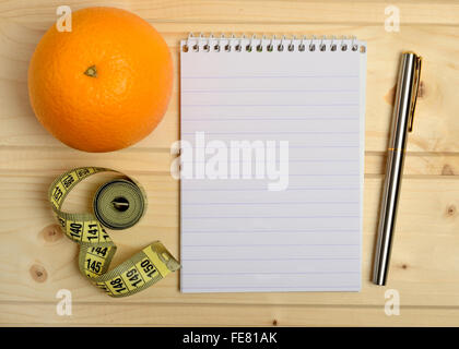 Notebook with orange fruit and centimeter on wooden table Stock Photo