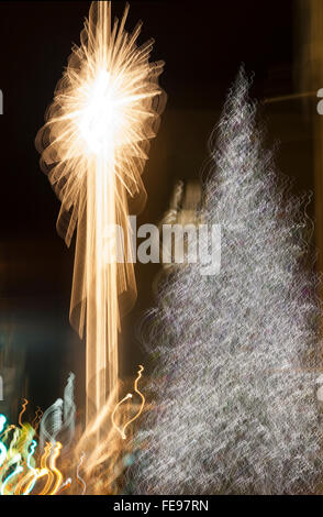 Abstract Christmas tree and lights in city at night. Bright holiday decorations background. Stock Photo