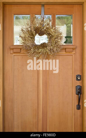 Beautiful gold wreath hanging on wooden front door. Simple, natural, elegant Christmas holiday home decorations. Stock Photo