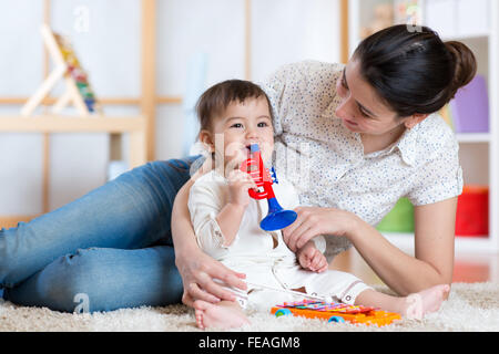 baby and her mother play musical toys Stock Photo