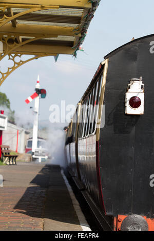 Bala Departure, in bright sunshine a train leaves the station on the Bala Lake Railway, focus on the tail lamp at the rear. Stock Photo