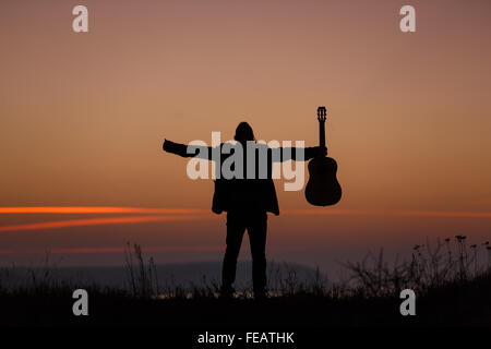 Man standing with guitar in sunset time Stock Photo