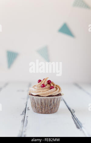 one cupcake with frosting and berries on wooden background Stock Photo