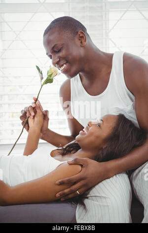 Woman resting on the legs oh her boyfriend holding a rose Stock Photo