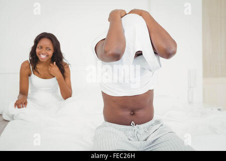 Man putting a shirt on with girlfriend watching Stock Photo