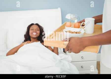 Man bringing breakfast in bed to his girlfriend Stock Photo