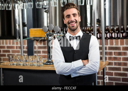 Handsome barman smiling at camera with arms crossed Stock Photo