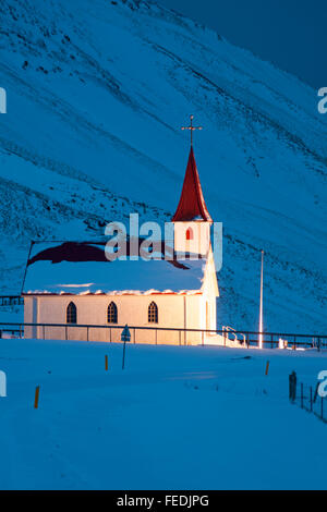 Snow covered Ingjaldsholl church, Ingjaldsholskirkja, at twilight at Hellisandur with Snaefellsjokull, Snaefellsnes Peninsula, Iceland in January Stock Photo