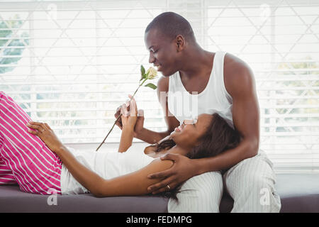 Woman resting on the legs oh her boyfriend holding a rose Stock Photo