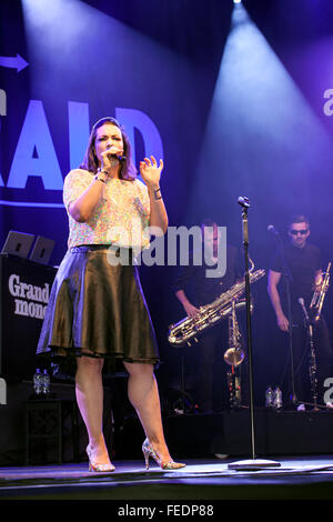 Singer with a microphone on stage. Man playing a saxophone with blue shafts of light in the back ground. Stock Photo