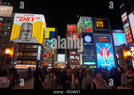 People crossing a canal by bridge with neon signs in the commercial area, Osaka, Japan Stock Photo