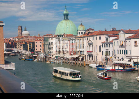 Vaporetto waterbus water bus boat public transport on Grand Canal approaching Ferrovia Railway station stop with churches onf Sa Stock Photo