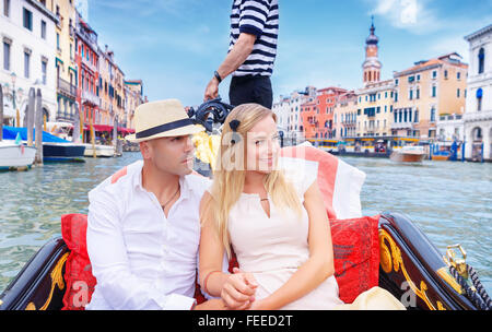 Young happy couple riding on a gondola on Grand Canal in Venice, with pleasure spending honeymoon in Europe Stock Photo