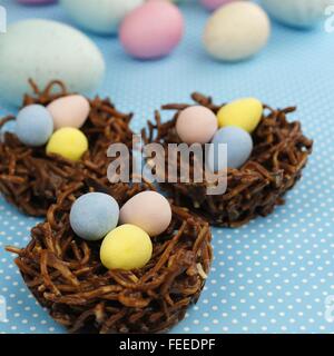 Springtime chocolate nests filled with Easter eggs on a blue background Stock Photo