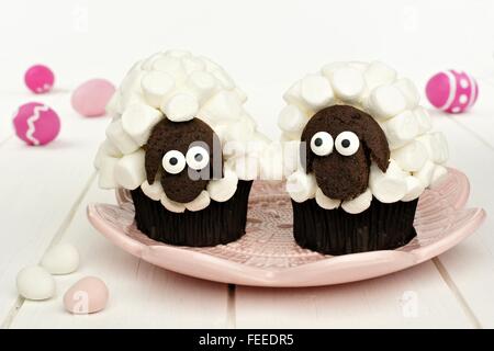 Cute spring sheep cupcakes on pink plate with Easter eggs Stock Photo