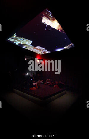 Visitors lying on a bed like platform, while watching images of the skies above Yeman, Somalia and Pakistan overhead, as part of the installation of Astro Noise, the first solo exhibit by artist Laura Poitras at the Whitney Museum of American Art in New York City on February 3, 2016.  Later in the exhibit thermal images captured while people lay in this room, are displayed.  Poitras, a filmmaker, artist and journalist best known for helping to break the Edward Snowden story, created the exhibition as an immersive multimedia experience examining topics such as mass surveillance, the war on terr