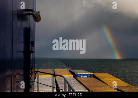 Rainbow rising over the horizon on the North Sea, seen from the deck of a cargo ship Stock Photo