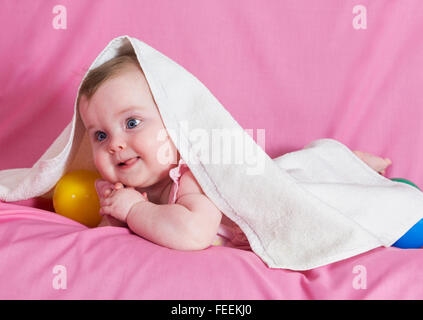 Adorable happy baby girl with white  towel on pink background Stock Photo