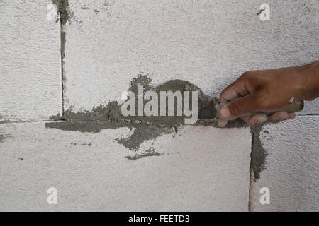 hand using trowel with wet concrete to plastering lightweight Concrete block, Foamed concrete block, raw material for industrial Stock Photo