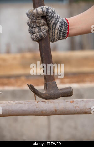 hammer pulling a nail out of wood at construction site Stock Photo