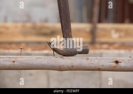 hammer pulling a nail out of wood at construction site Stock Photo