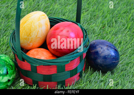 colorful Easter eggs in a basket, outside on green grass, close up, full frame,  horizontal Stock Photo