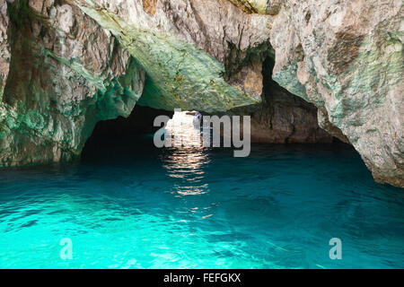 Coastal rocks of Capri island, small empty grotto with shining sea water inside Stock Photo