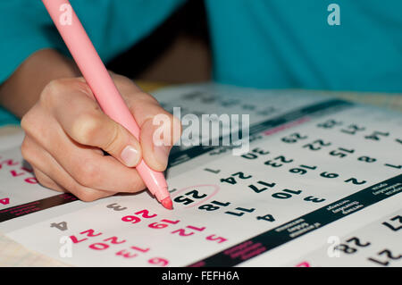Close-up photo of calendar with a datum circled by kid's hand with a pink marker, concept of time management at work Stock Photo