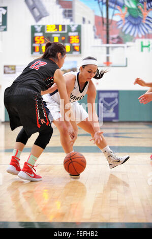 Two players battle for possession of a loose ball in the lane during a high school basketball game. USA. Stock Photo