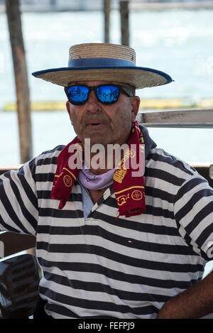 A gondoliere wearing his blue & white striped shirt and boater with a blue band in Venice, Italy Stock Photo