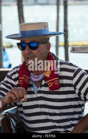A gondoliere wearing his blue & white striped shirt and boater with a blue band in Venice, Italy Stock Photo