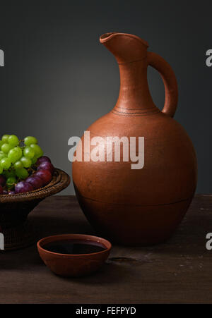red wine with grapes and a pitcher on a wooden table Stock Photo
