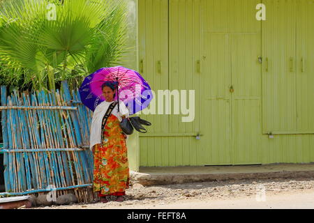 DEBRE BIRHAN-ETHIOPIA-MARCH 24: Local young woman with umbrella waits for the bus to come while standing on the main street. Stock Photo
