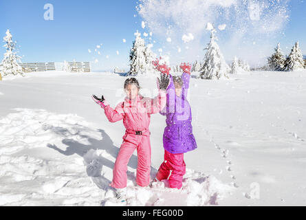 Two Little girls playing with snow and  having fun Stock Photo
