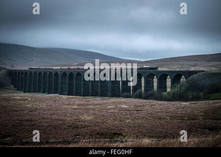 Ribblehead, near Settle, North Yorkshire. Saturday 6th February 2016. One of the world's most famous locomotives, the Flying Scotsman, has returned to the West Coast mainline following a £4.2m, 10 year restoration project. Travelling from Carnforth on the West Coast Main Line to Carlisle and then returning via the historic Settle Carlisle Railway, the train is pictured crossing the  Ribblehead Viaduct at dusk. The engine was retired from service in 1963 and has been restored for the York's National Railway Museum by Riley and Son Ltd, based in Bury. Credit: Ian Wray/Alamy Live News Stock Photo