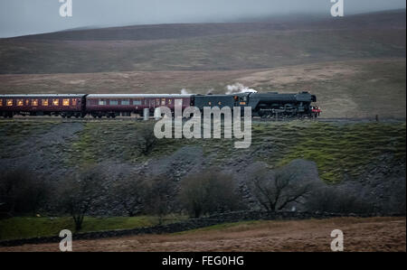 Ribblehead, near Settle, North Yorkshire. Saturday 6th February 2016. One of the world's most famous locomotives, the Flying Scotsman, has returned to the West Coast mainline following a £4.2m, 10 year restoration project. Travelling from Carnforth on the West Coast Main Line to Carlisle and then returning via the historic Settle Carlisle Railway, the train is pictured crossing the  Ribblehead Viaduct at dusk. The engine was retired from service in 1963 and has been restored for the York's National Railway Museum by Riley and Son Ltd, based in Bury. Credit: Ian Wray/Alamy Live News Stock Photo