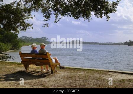 Couple sitting on a bench overlooking the Matanzas river, Washington Oaks Gardens State Park, Florida Stock Photo