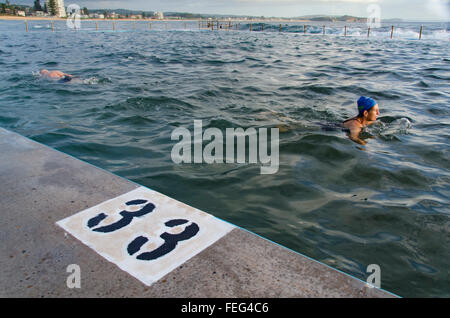 With a large number 33 painted on the pool edge, people swim in an ocean pool at Collaroy Beach in Sydney, New South Wales, Australia Stock Photo