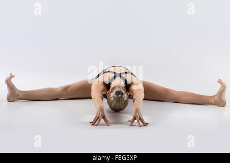 Sporty beautiful young woman practicing yoga, doing Upavishtha Konasana, Wide-Angle Seated Forward Bend, Straddle (dragonfly) Stock Photo