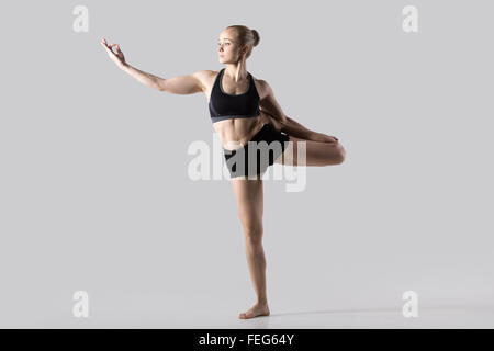 Sporty beautiful young woman practicing yoga, doing variation of Natarajasana, Lord of the Dance or King Dancer Pose Stock Photo