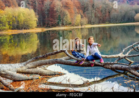 Two little girls laughing and pointing fingers on Lake Biograd (Biogradsko ezero), Biogradska Gora national park in autumn, Mont Stock Photo