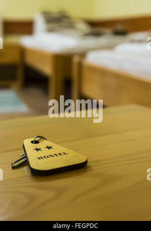 A key of a two stars hostel room is on a wooden table. Selective focus. Stock Photo
