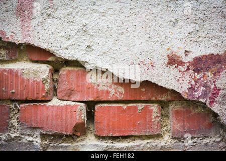 Red bricks showing through white broken plaster Stock Photo