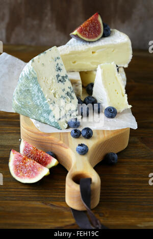cheeses and fruits on board, food closeup Stock Photo