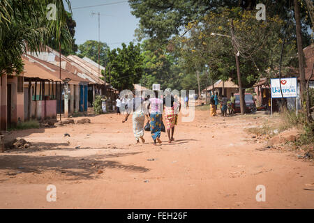 Villagers walk down the unpaved street in a northern Guinea Bissau town Stock Photo