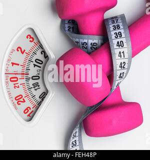 Scales and measuring tape on pink background. Weight loss concept